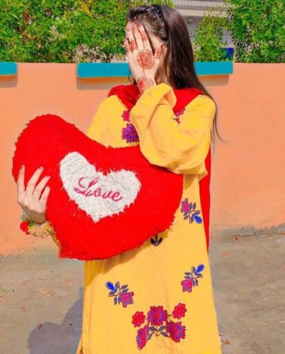 girl in yellow dress hiding her face with her hand and holding heart with love